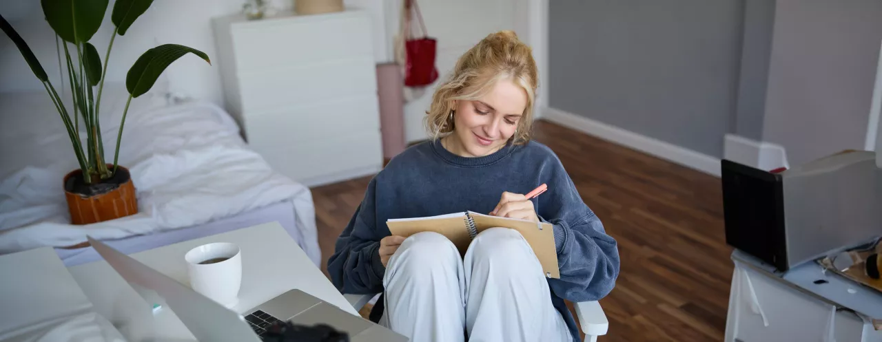 portrait-young-woman-writing-diary-making-notes-notebook-sitting-chair-room